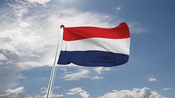 Nederlandse vlag wappert tegen een halfbewolkte blauwe lucht