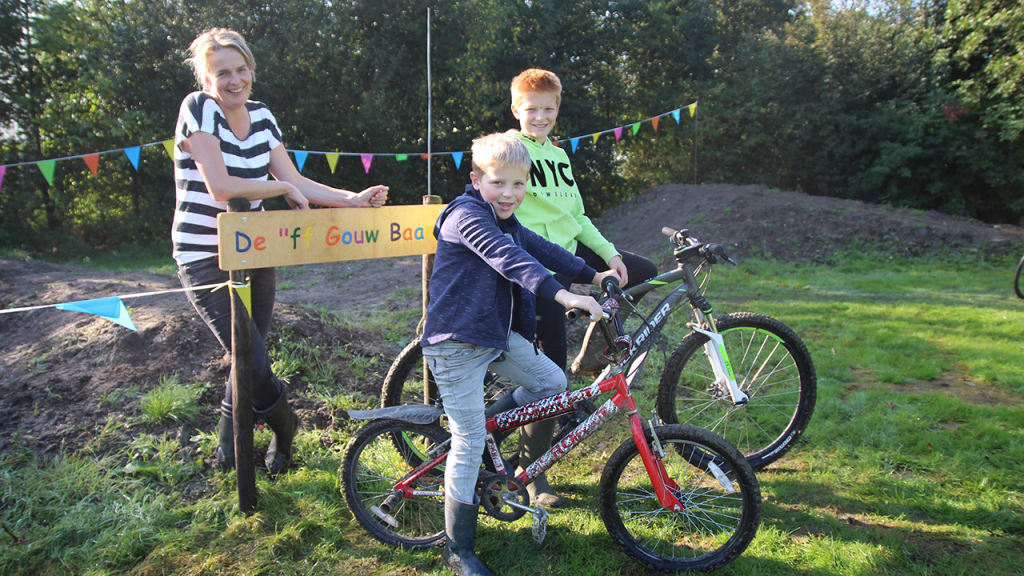 Mariska van Wijk met zoon Jurre en neefje Mike op crossfietsen bij het naambord van de fietscrossbaan